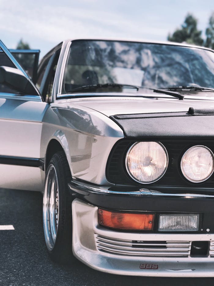 Close-up of a vintage silver car showcasing classic headlights and shiny chrome elements.