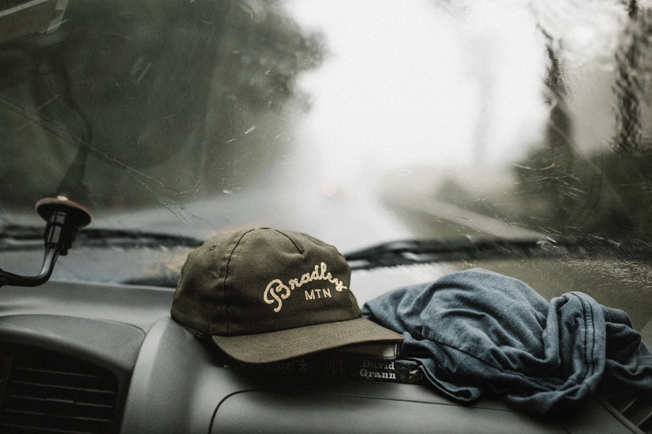 Close-up of a car interior during a rainy drive in North Carolina with a hat on the dashboard.