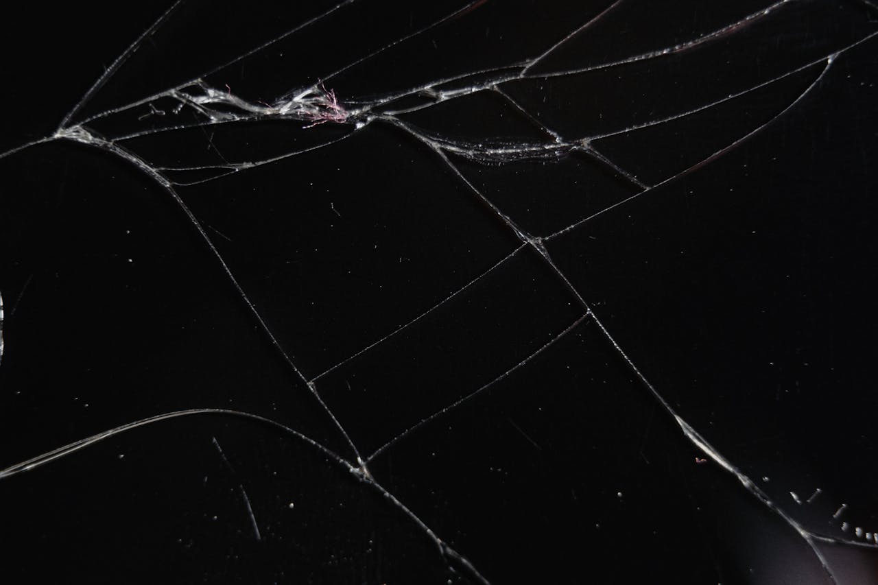 about-us Close-up of a cracked glass surface displaying intricate patterns and reflections.
